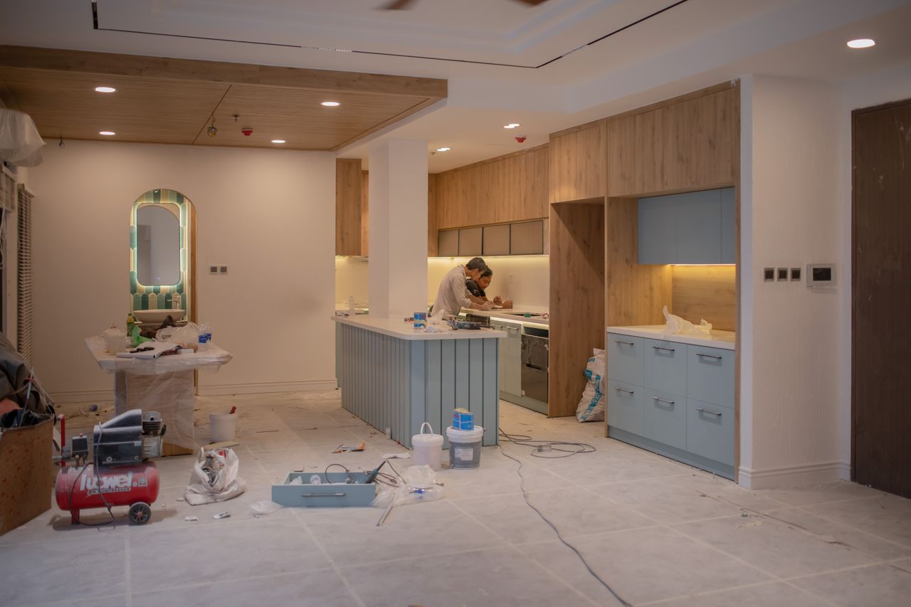 Une cuisine contemporaine en pleine rénovation, avec un ouvrier, des outils et des matériaux.